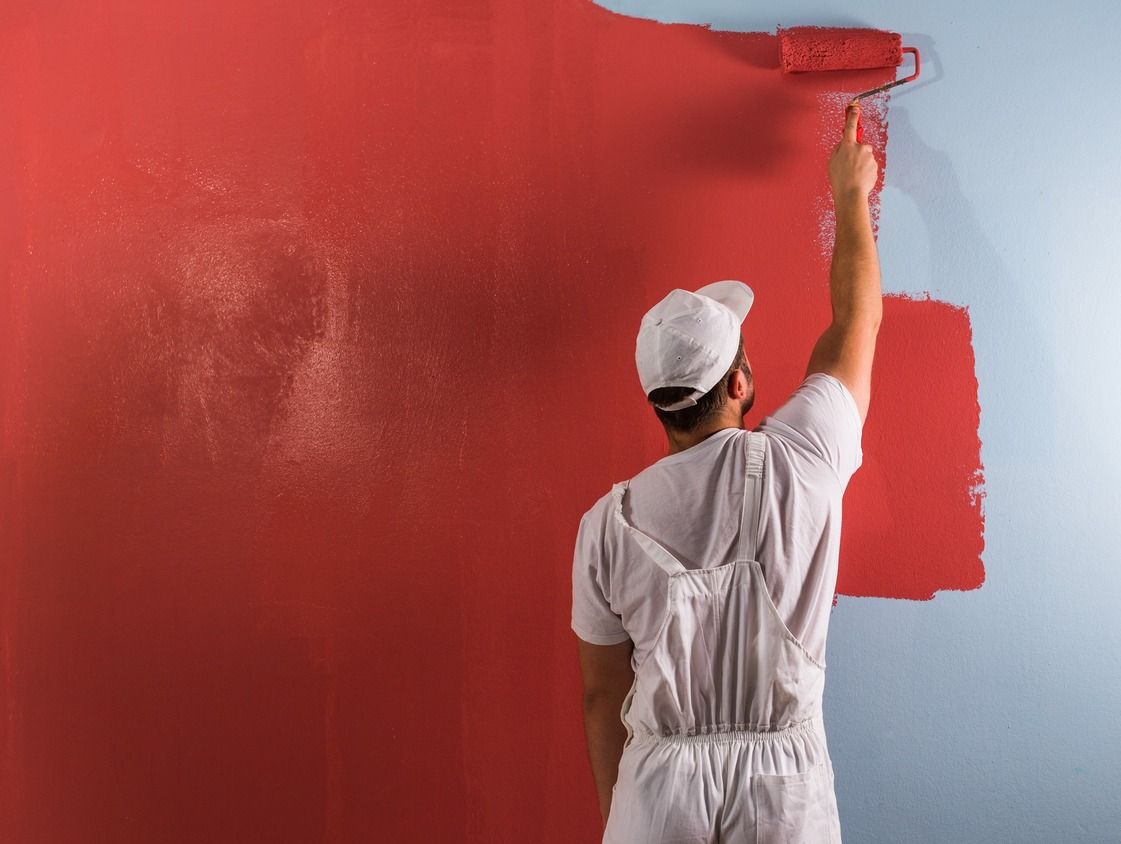 pintor profesional imprime rojo a rodillo en pared